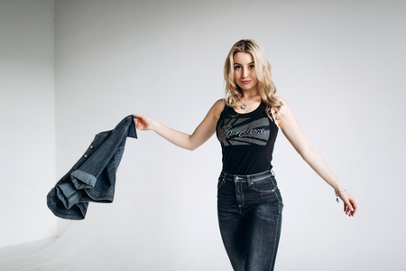 Portrait of a beautiful fashion woman, blonde, jeans, gray backgroundの写真素材