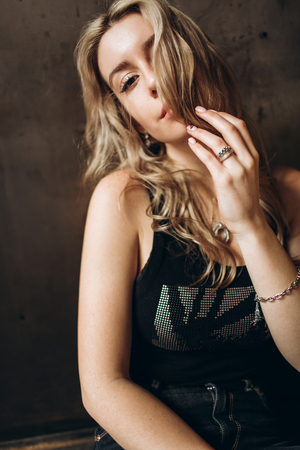 Portrait of a beautiful fashionable woman, blonde, jeans, brown backgroundの写真素材