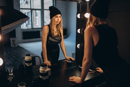 Portrait of a beautiful fashionable woman, blonde, jeans, posing in front of a mirrorの写真素材