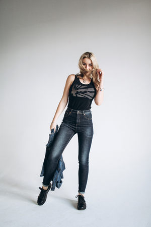 Portrait of a beautiful fashion woman, blonde, jeans, gray backgroundの写真素材