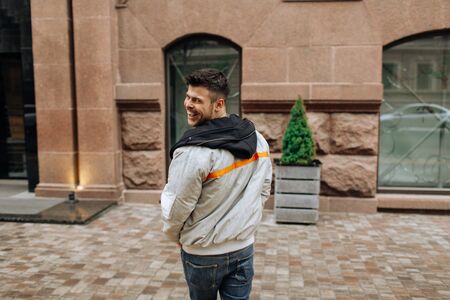 Portrait of a young man walking around the city. Brunette, beard. Cheerful, beautiful smile.の写真素材