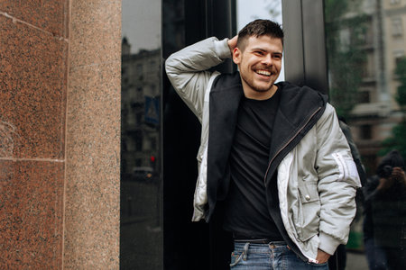 Portrait of a young man walking around the city. Brunette, beard. Cheerful, beautiful smile.の写真素材