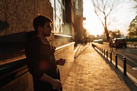 Young man smokes at sunset in the middle of the cityの写真素材