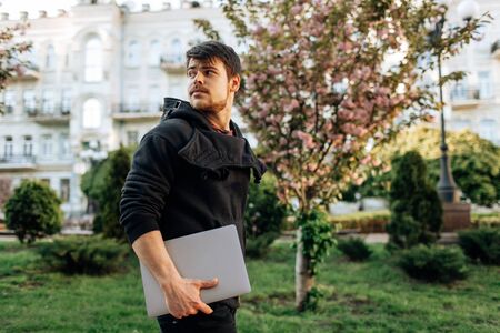 Successful asian businessman walking in the street, holding a laptop in his handの写真素材