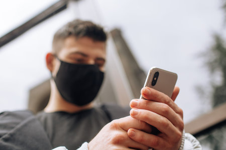 Brunette in a black T-shirt and jacket in a black face mask. Talking on the phone. Black stylish...
