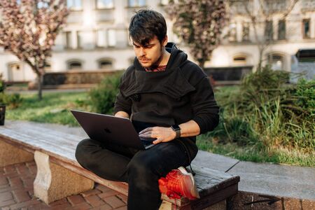 Young male working on his laptop computer in the city center. An independent person typing something in his document. chatting with friends over the internet, webcamの写真素材