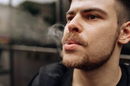man smokes a cigarette. The spread of cigarette smoke. mustacheの写真素材