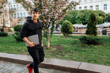 Successful asian businessman walking in the street, holding a laptop in his hand