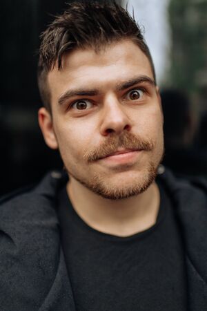 Portrait of a young man walking around the city. Brunette, beard. Cheerful, beautiful smile.の写真素材
