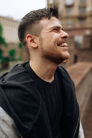 Portrait of a young man walking around the city. Brunette, beard. Cheerful, beautiful smile.の写真素材