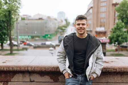 Portrait of a young man walking around the city. Brunette, beard. Cheerful, beautiful smile.の写真素材