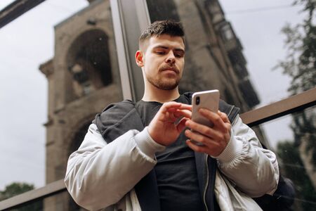 Portrait of happy young man walking on the street and looking aside while talking by his phone.の写真素材