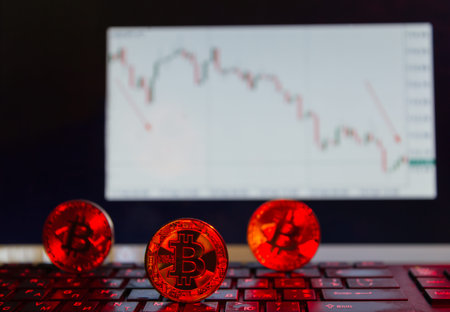 bitcoin on the keyboard in red, on the background of the descending chart