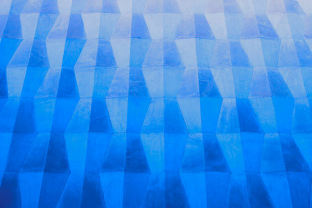 Old painted wall with a convex surface. Background of geometric shapes in blue in various shades....