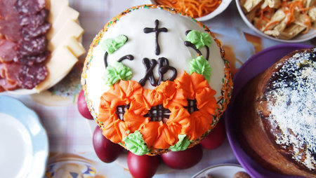 Decorating with flowers from bright glaze on a traditional Easter kulich. Authentic Christian...