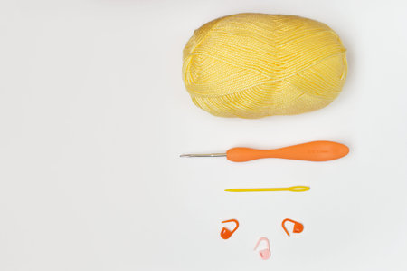 Top view of a skein of yellow yarn, crochet hook, needle and row counters. Colorful accessories for...