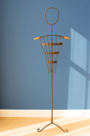 Vertical high hanger for clothes against the backdrop of a blue wall. Metal coat rack, mannequin. Space for textの写真素材