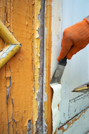 Cleaning an old wooden front door from layers of paint. Repair in the household. Removing the painted coating with a building hair dryer and a spatula. Hand tools. Selective focusの写真素材