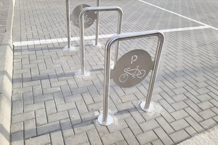Empty bicycles parking. Place for parking at the house or shop for multiple bikes. New metal parking posts with traces of cement from construction.の写真素材