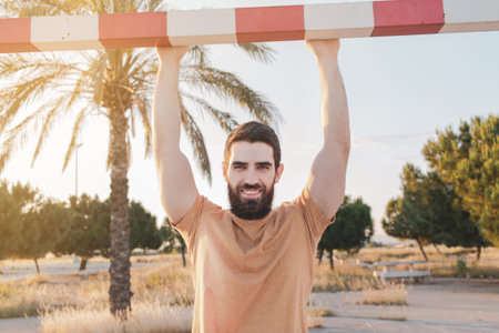 Handsome young man outdoors portrait. Man smiling, looking at the camera with his hands up holding a...