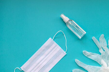 Face mask, plastic and transparent gloves and antiseptic gel on a blue background.の写真素材