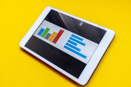 Tablet with diagram and report on a blue background. Office environment and Business concept.の写真素材