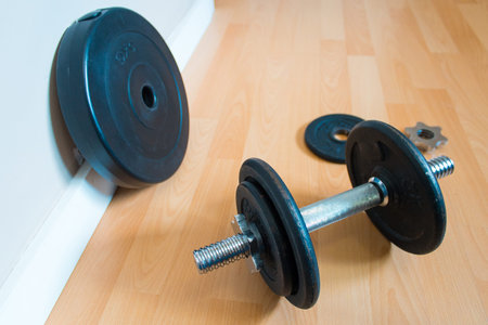Dumbbell with black discs on wooden platform. Training at home concept.の写真素材