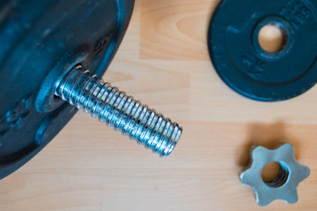Dumbbell with black discs on wooden platform. Training at home concept.