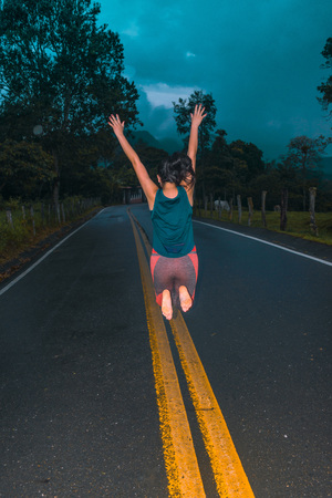 FREE GIRL JUMPING ON THE ROAD IN THE DARK AFTERNOONの写真素材