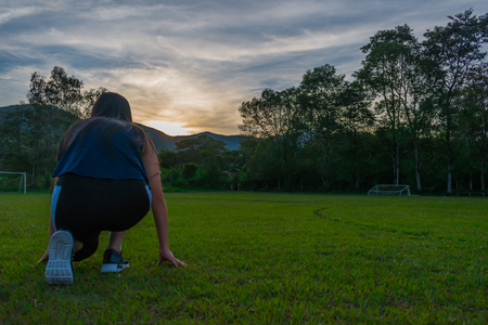 YOUNG WOMAN DOING EXERCISE AT SUNSETの写真素材