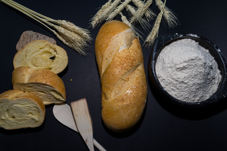 still life of bread and wheat flour on black background decorated with spikesの写真素材