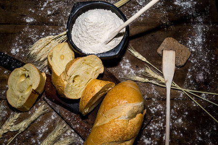 still life of bread and wheat flour on black background decorated with spikes