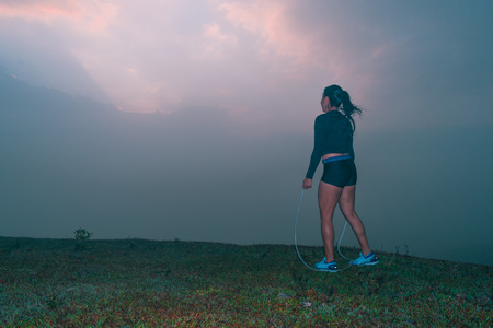 WOMAN PERFORMING STRETCHING EXERCISES AT SUNRISEの写真素材