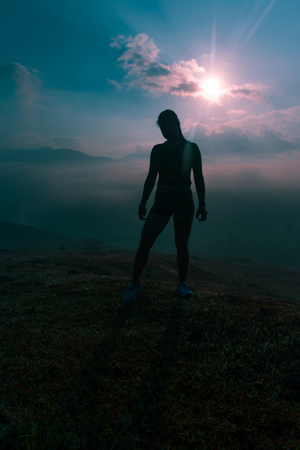 SILHOUETTE OF FEMALE ATHLETE ON THE MOUNTAIN AT SUNRISEの写真素材
