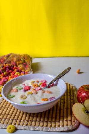 HEALTHY BREAKFAST OF COLORFUL CEREAL IN MILK AND APPLEの写真素材
