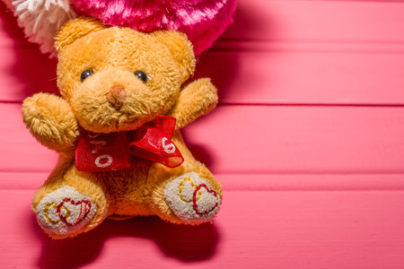 small yellow teddy bear on pink wooden background with space to place textの写真素材