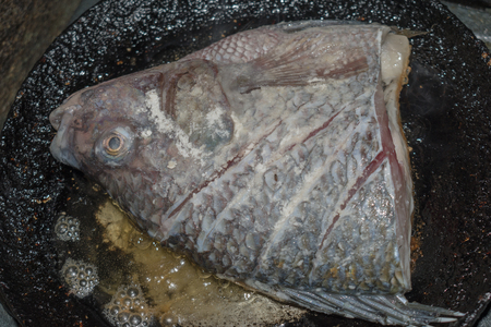 overhead view of half fish fried in old iron skilletの写真素材