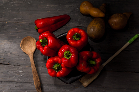 STILL LIFE WITH OVERHEAD VIEW OF RED PEPPERS ON A RUSTIC WOODEN TABLE DECORATED WITH OLD CLOTH AND DRIED PUMPKINSの写真素材