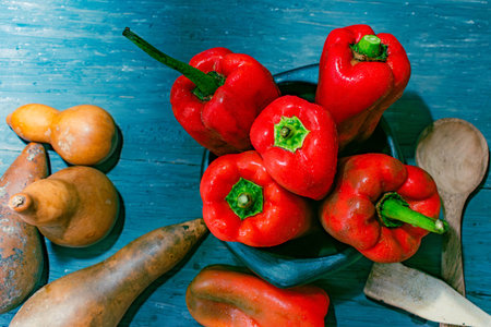 overhead shot of fresh red peppers just harvested and dried pumpkins on old wood