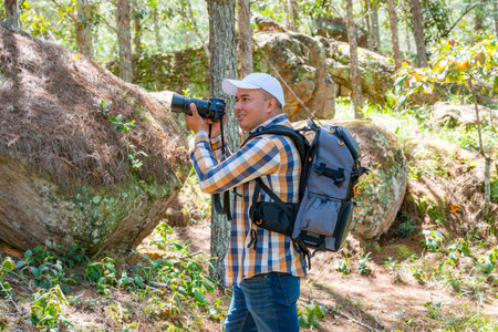 Latin American male photographer lifts his camera to eye level to look through the viewfinder and...