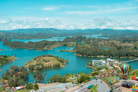 GuatapÃ© reservoir dotted with lush green islands and clear blue water, lively waterfront with...