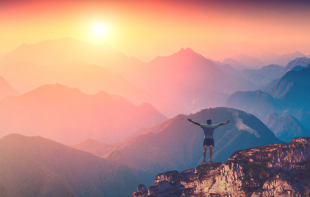 Man with raised hands standing on a mountain top and welcome sunrise in a Carpathian mountains Man with raised hands standing on a mountain top and welcome sunrise in a Carpathian mountains