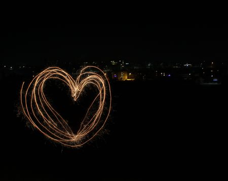 Heart symbol created by light on the background of night cityの写真素材