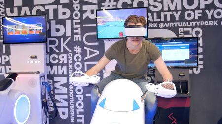 Young attractive handsome guy rides a motorcycle in virtual reality. Holidays, innovation, screen, neon, bike, cool, entertainment, vr, vr clubの写真素材