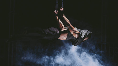 Young acrobat hangs in the air at the ropes