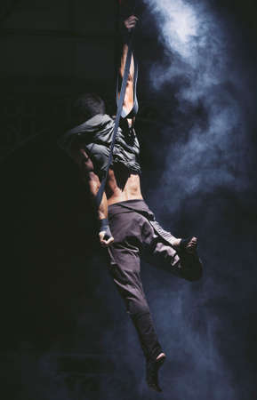 Acrobat on the strings moving a circle above a ground in hard practice.の写真素材