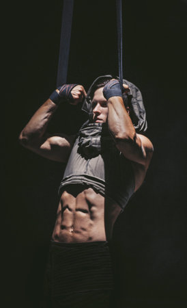 Young bodybuilder pull himself up on the ropes