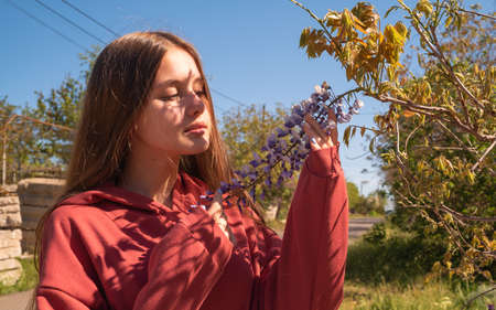 Cute girl in red hoodie looks on beauty flowersの写真素材