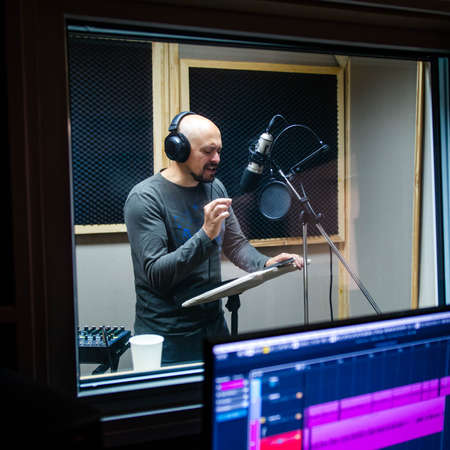Bald man near microphone recording voice.の写真素材