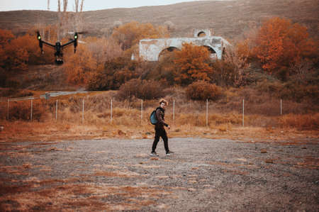 Young curly man trying to run away from drone securityの写真素材
